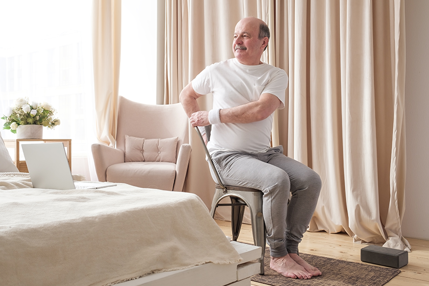 Sporty senior man practicing yoga using chair