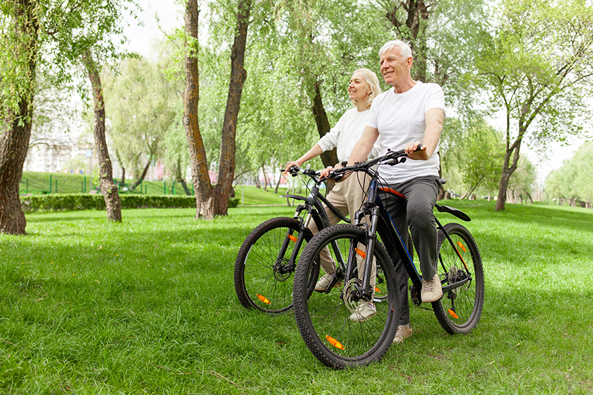 Elderly senior couple rides bicycle in the park