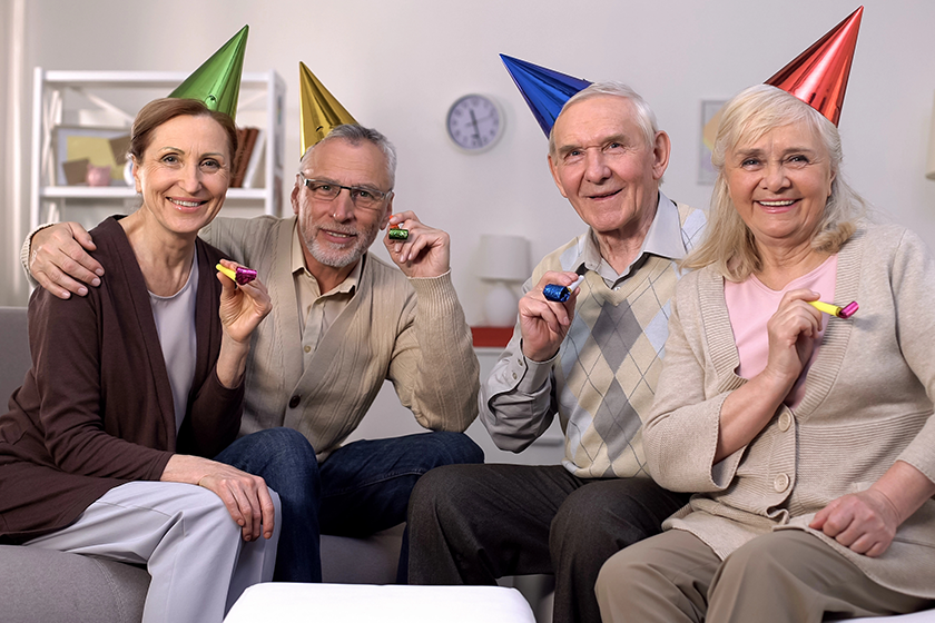 smiling-aged-group-people-party-hats-looking-camera